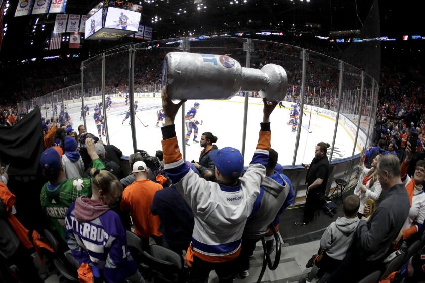 FILE - In this April 10, 2019, file photo, New York Islanders players take the ice as a man holds a makeshift Stanley Cup prior to Game 1 of an NHL hockey first-round playoff series against the Pittsburgh Penguins in Uniondale, N.Y. (AP Photo/Julio Cortez, FIle)