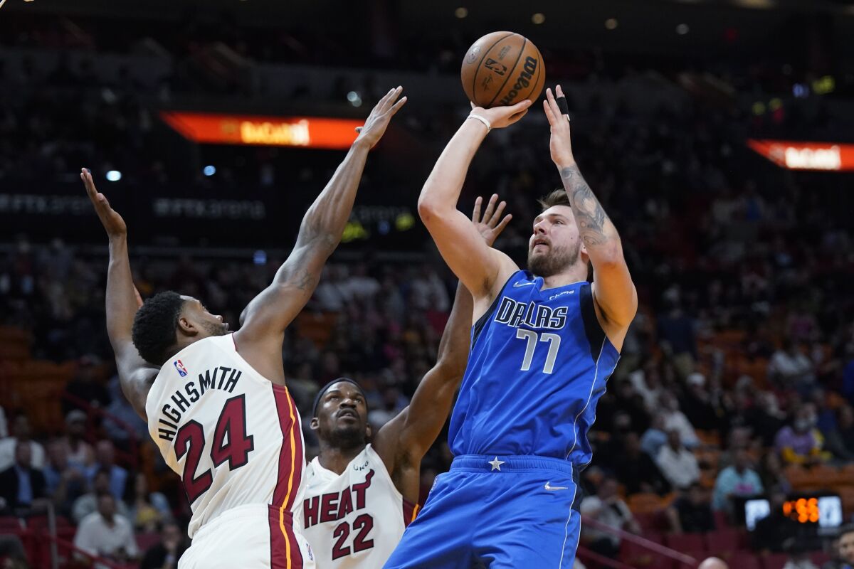 Dallas Mavericks guard Luka Doncic (77) attempts a shot against Miami Heat forwards Haywood Highsmith (24) and Jimmy Butler (22) during the first half of an NBA basketball game, Tuesday, Feb. 15, 2022, in Miami. (AP Photo/Wilfredo Lee)