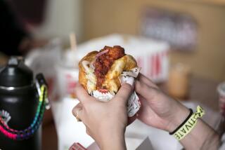 LOS ANGELES, CALIFORNIA - Oct. 23, 2019: A customer prepares to bite into Sando, Howlin' Ray's signature fried-chicken sandwich on Monday, Oct. 23, 2019, at the popular restaurant in Chinatown, downtown Los Angeles. (Photo / Silvia Razgova) Assignment ID: 469966