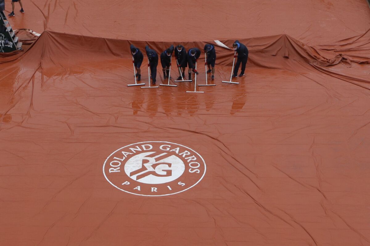 Stadium workers remove rain water from the cover of Suzanne Lenglen court as rain delayed fourth round matches of the French Open tennis tournament at the Roland Garros stadium in Paris, France, Monday, Oct. 5, 2020. (AP Photo/Alessandra Tarantino)