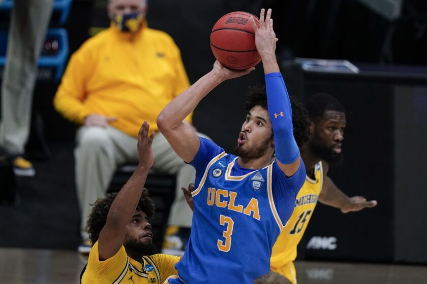 UCLA guard Johnny Juzang (3) shoots over Michigan guard Mike Smith, left, during the first half of an Elite 8 game.