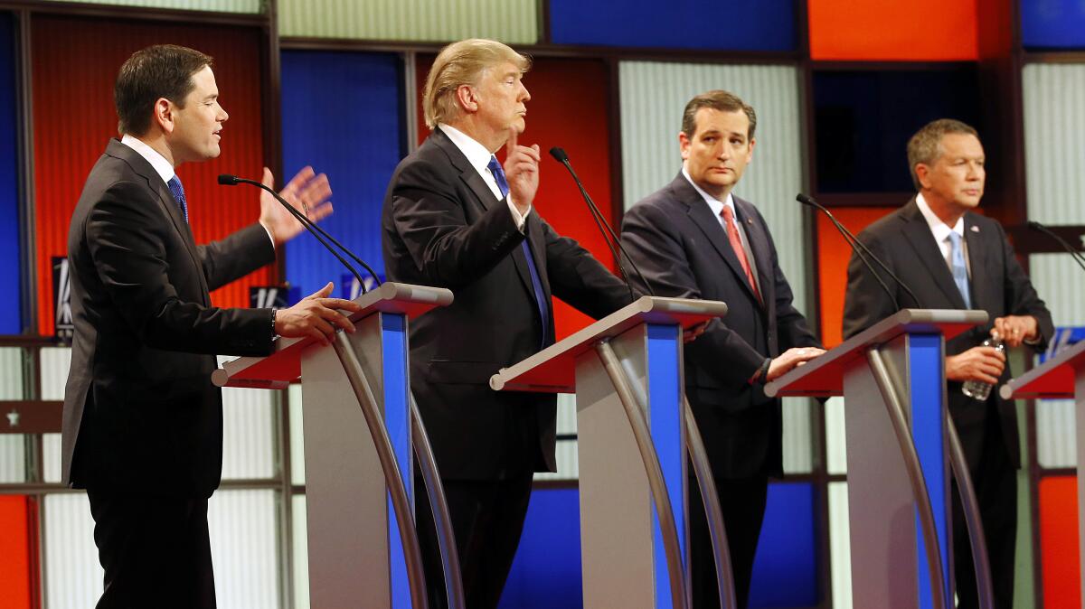 Four men behind lecterns on a debate stage 
