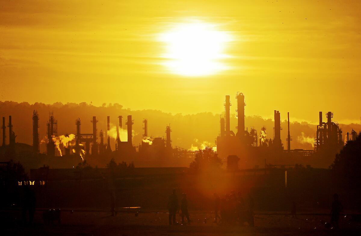 An oil refinery silhouetted against a low sun.
