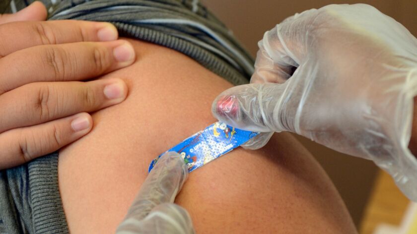 A child receives a whooping cough vaccine booster shot.
