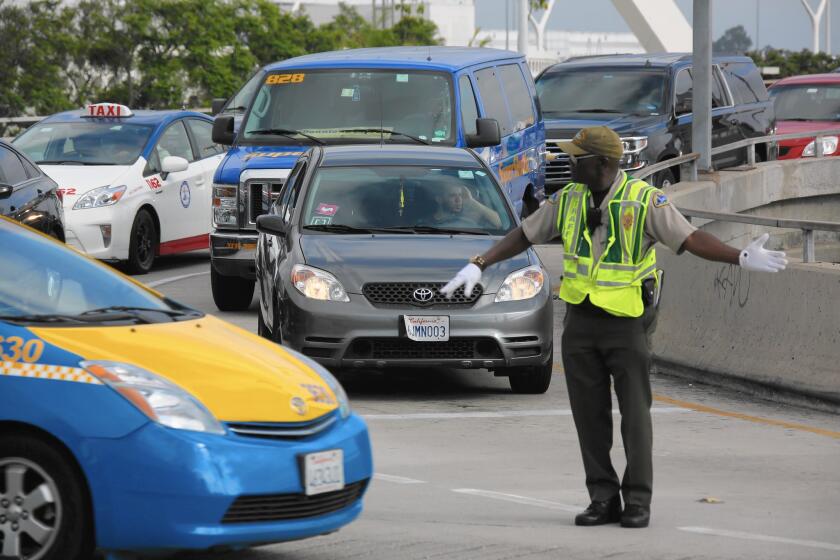 A car with Uber and Lyft stickers leaves the departure terminal at Los Angeles International Airport. Uber has earned the right to legally pick up and drop off fliers from LAX, which was previously reserved for taxis.