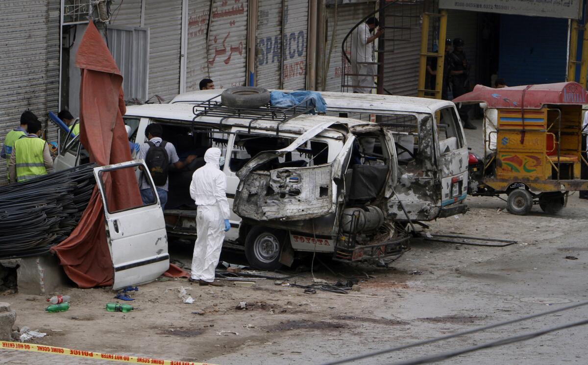 Pakistani investigators examine damaged vehicles at the site of a suicide bombing Wednesday in Lahore.
