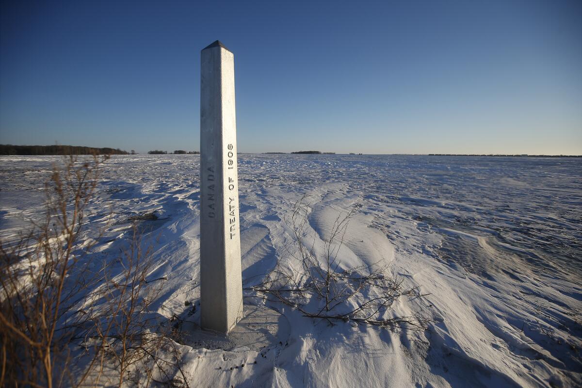 A border marker, between the United States and Canada is shown just outside of Emerson, Manitoba, on Thursday, Jan. 20, 2022. A Florida man was charged Thursday with human smuggling after the bodies of four people, including a baby and a teen, were found in Canada near the U.S. border, in what authorities believe was a failed crossing attempt during a freezing blizzard. The bodies were found Wednesday in the province of Manitoba just meters (yards) from the U.S. border near the community of Emerson. (John Woods/The Canadian Press via AP)