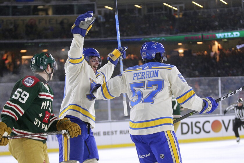 St. Louis Blues left wing David Perron (57) and left wing Brandon Saad (20) celebrate Perron's goal with Minnesota Wild defenseman Calen Addison (59) skating by in the first period of the NHL Winter Classic hockey game Saturday, Jan. 1, 2022, at Target Field in Minneapolis. (AP Photo/Andy Clayton-King)