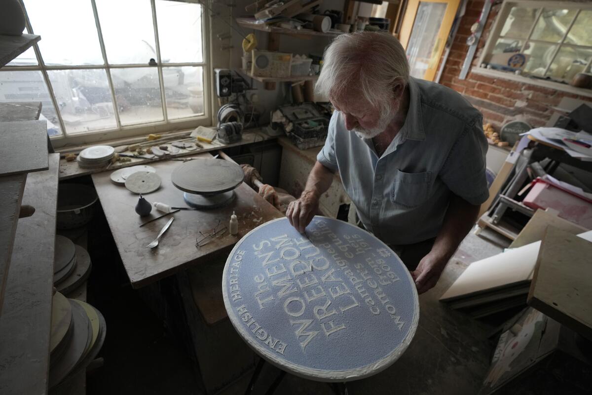Craftsman working on blue clay plaque used as historical marker in London