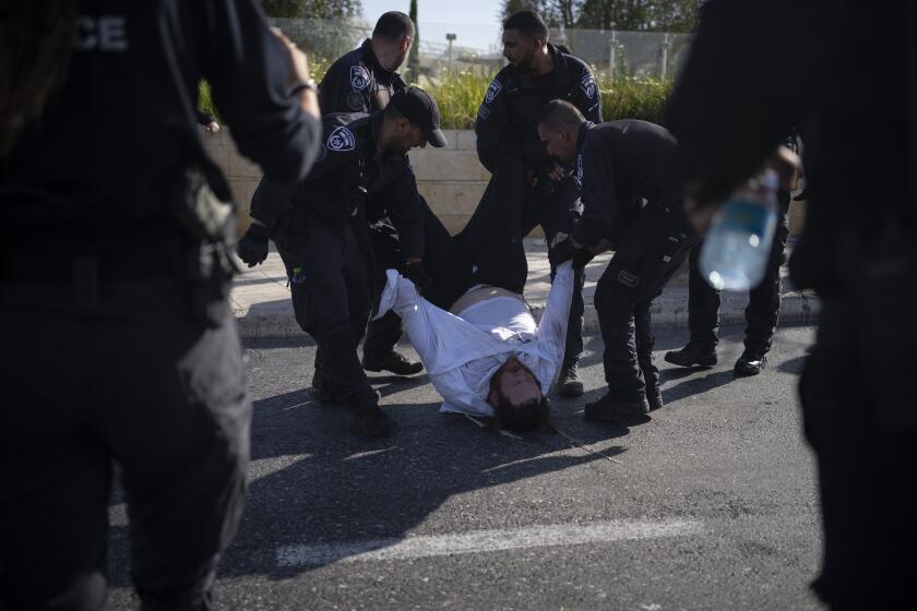 ARCHIVO - Agentes de policía israelíes se llevan a un hombre judío ultraortodoxo de la calle durante una protesta contra el reclutamiento militar en Jerusalén, el 2 de junio de 2024. (AP Foto/Leo Correa, Archivo)