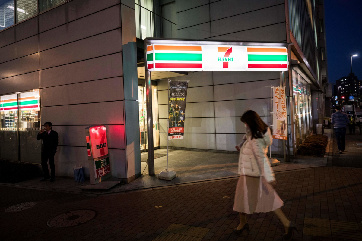 A woman walks past a 7-Eleven convenience store in Tokyo.