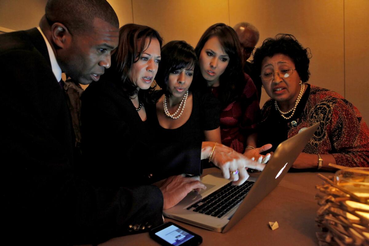 Kamala Harris surrounded by family members looking at a laptop.
