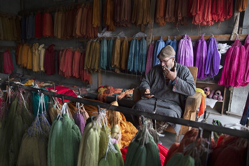 Shopkeeper Mohammad Ashraf browses the internet on his phone in Srinagar, Kashmir.