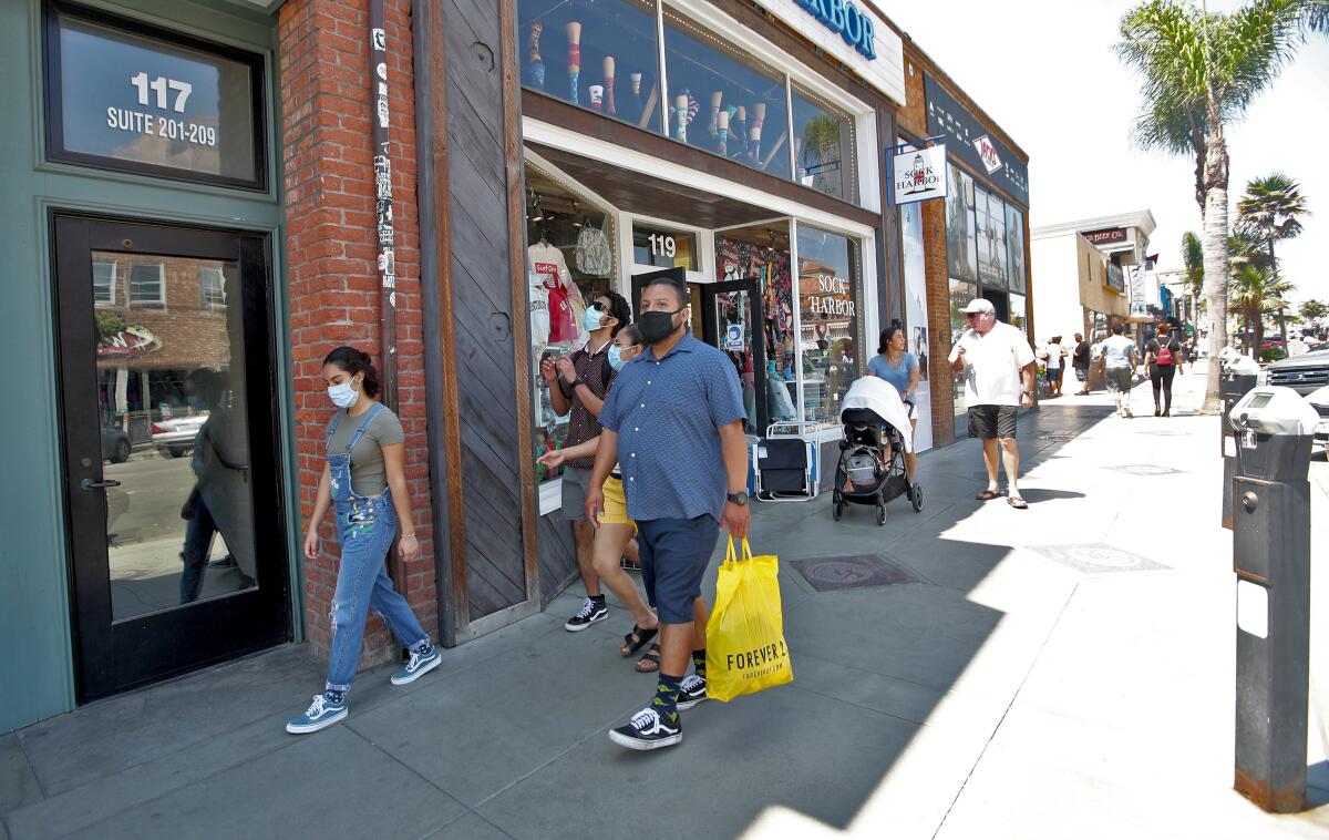 A family wears masks while shopping on Main Street in downtown Huntington Beach in June 2020. 