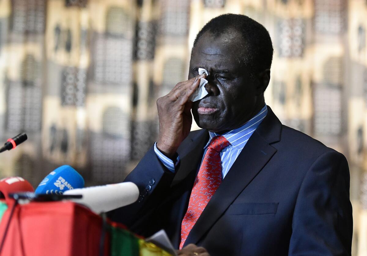 Burkina Faso President Michel Kafando wipes his face as he delivers a statement to the media on Sept. 23