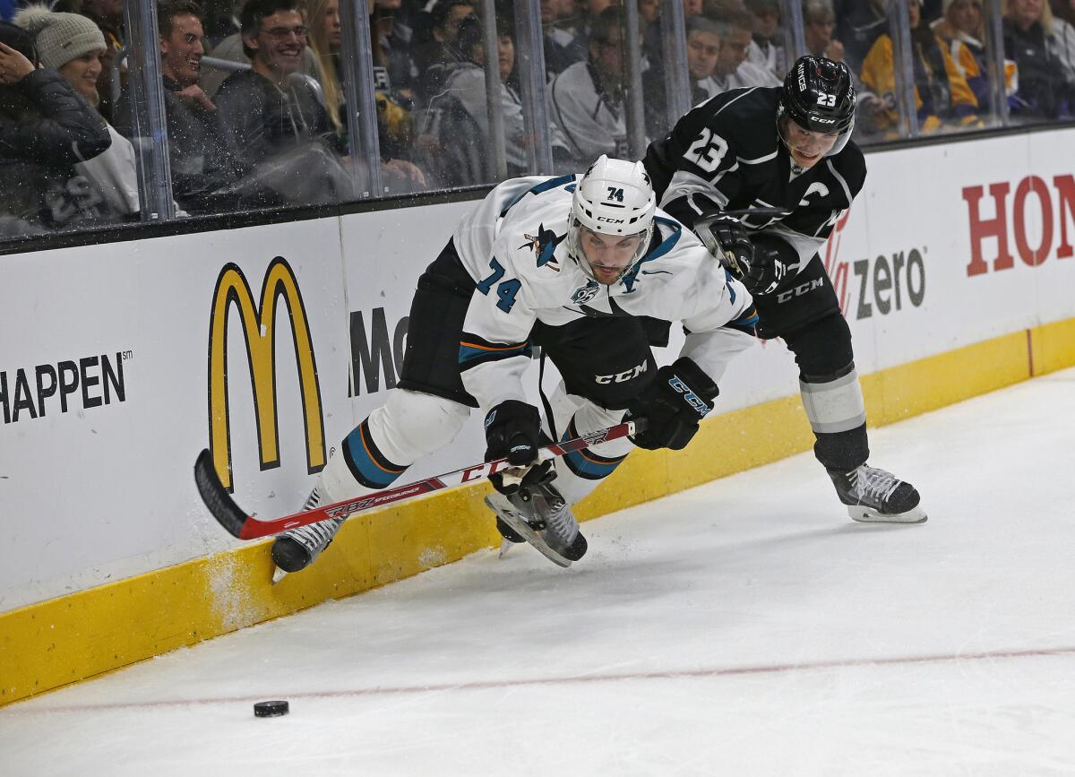 Kings right wing Dustin Brown (23) and Sharks defenseman Dylan DeMelo (74) battle for the puck against the boards in the third period on Dec. 22, 2015.