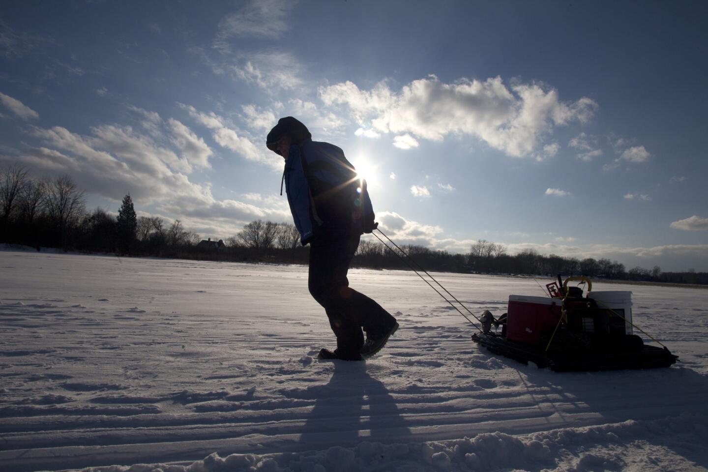 An ice fisherman makes his way back to his car after fishing on Independence Lake in Whitmore Lake, Mich.