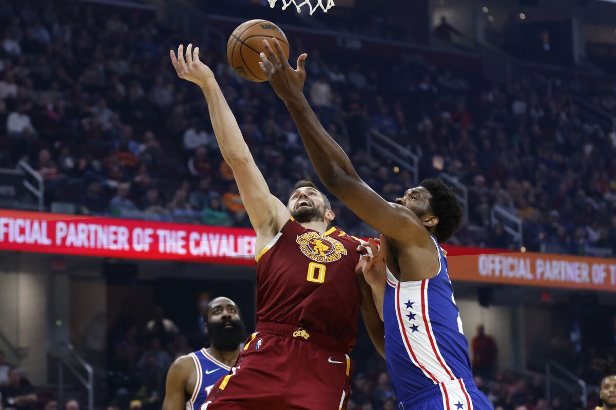 Cleveland Cavaliers' Kevin Love (0) and Philadelphia 76ers' Joel Embiid vie for a rebound during the first half of an NBA basketball game Wednesday, March 16, 2022, in Cleveland. (AP Photo/Ron Schwane)