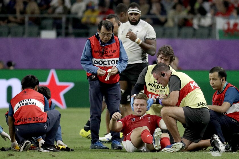 FILE - In this Oct. 9, 2019, file photo, Wales' Dan Biggar is assisted after he was injured during the Rugby World Cup Pool D game at Oita Stadium between Wales and Fiji in Oita, Japan. A "shadow trial" of advanced eye-tracking technology will be conducted in the Trans-Tasman Super Rugby tournament in Australia and New Zealand as part of World Rugby's bid to tackle head injuries by improving the detection of concussion. (AP Photo/Aaron Favila, File)