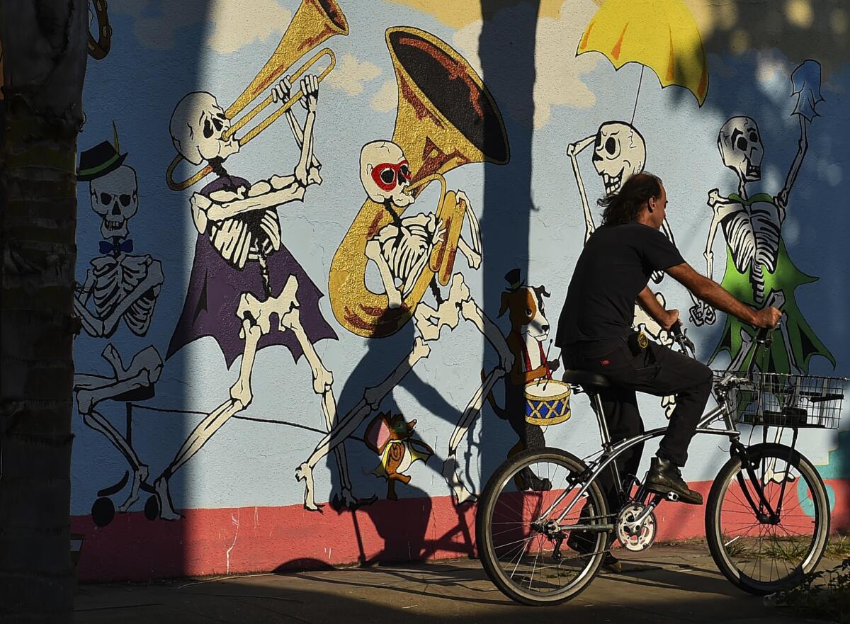 A bicyclist rides past a skeletal, jazz funeral-themed mural in the Bywater neighborhood.
