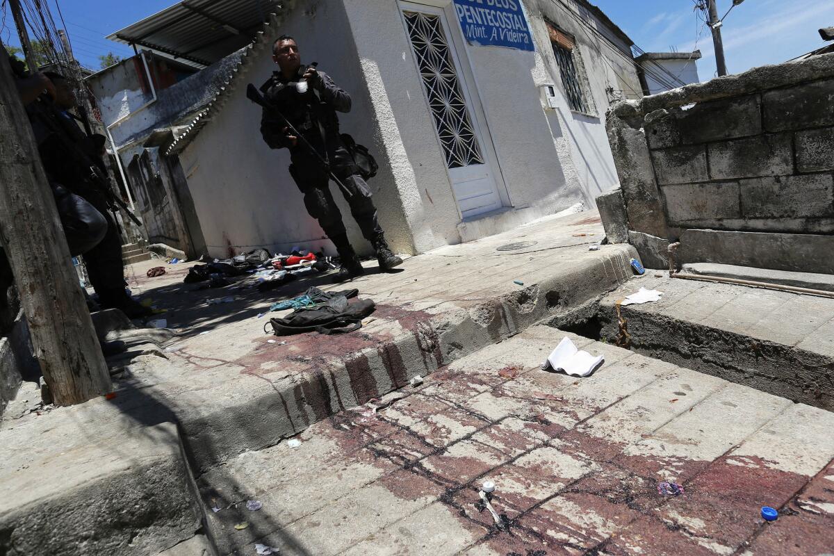 A Brazilian police officer stands by a blood-soaked walkway during a security operation in the Juramento slum in Rio de Janeiro.