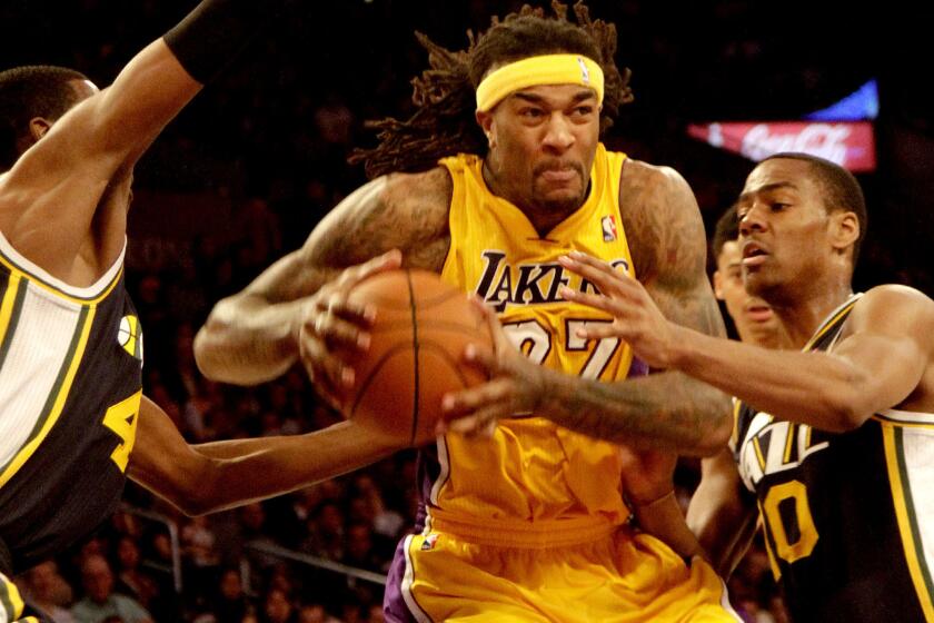 Lakers center Jordan Hill tries to power his way to the basket against the defense of Jazz forward Jeremy Evans, left, and guard Alec Burks during a game last season.