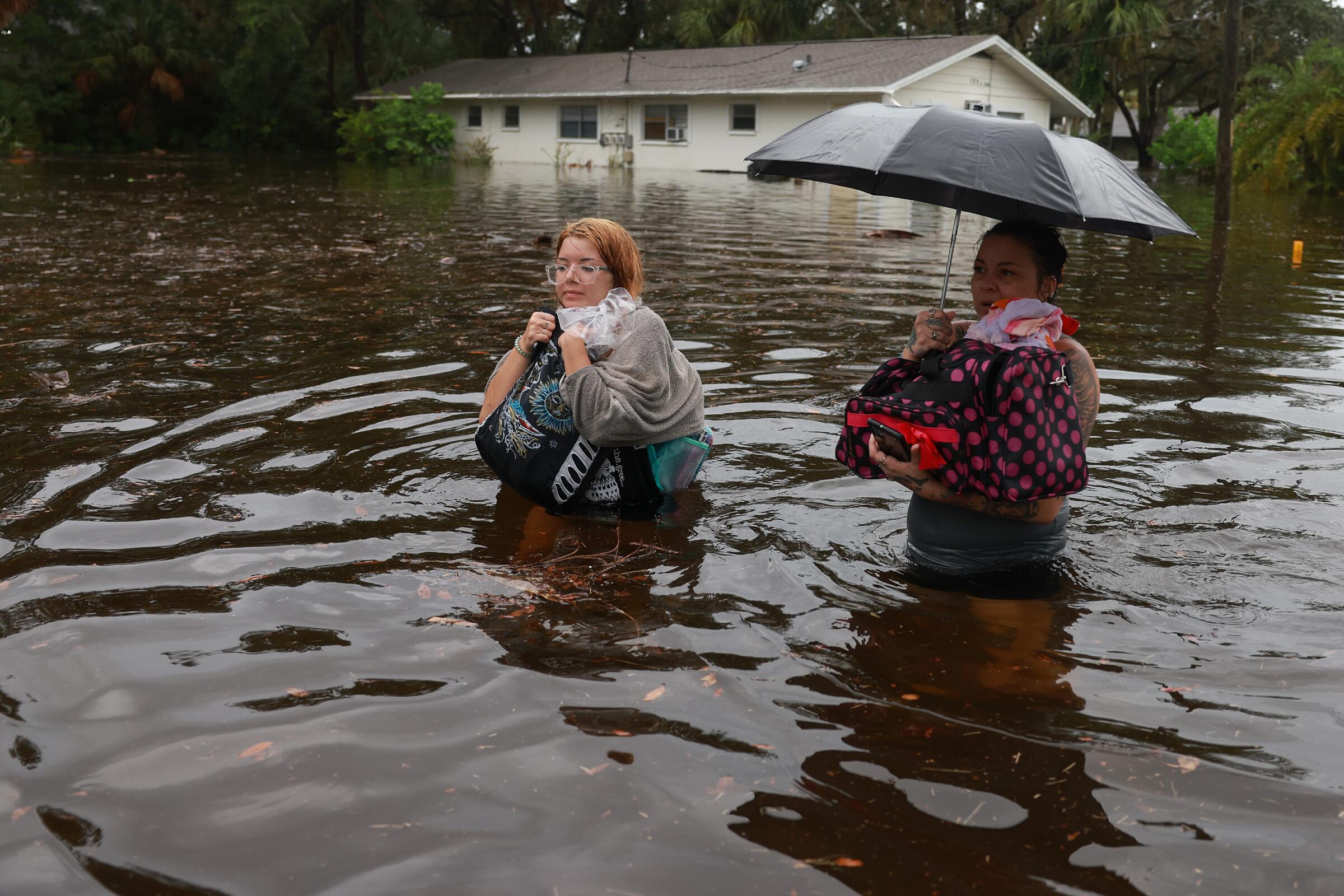 A mother and daughter wade through deep floodwaters.