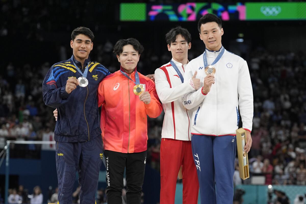 Four gymnasts celebrate on the podium after the men's horizontal bar final.