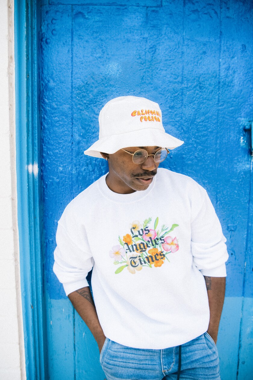 A man wearing a los Angeles Times sweatshirt and a white bucket hat 