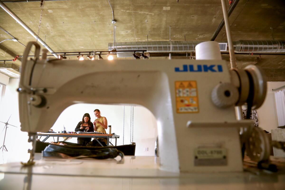 Two craftsmen are framed behind a sewing machine.