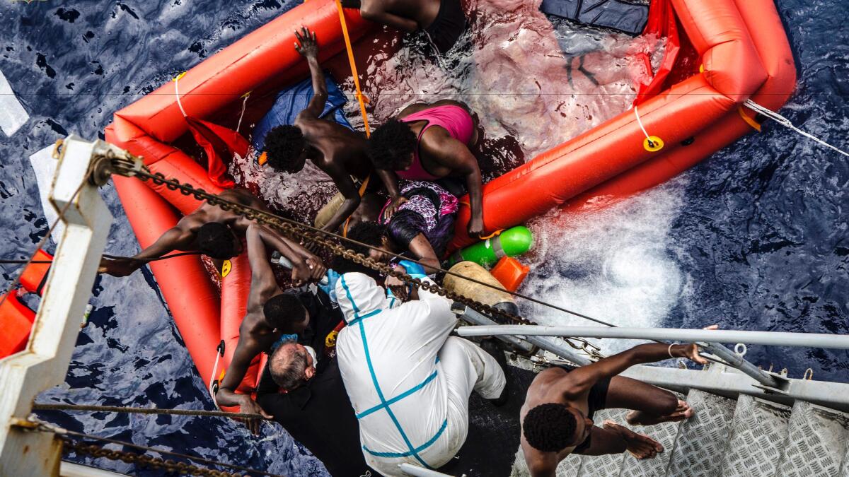 Rescuers help migrants board the Italian navy ship Vega after their boat went down off Libya.