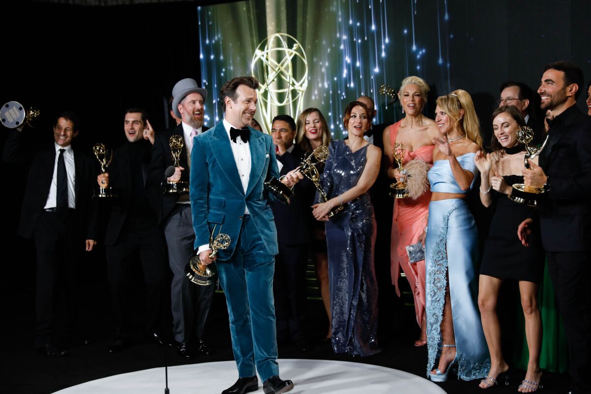 Jason Sudeikis, in a blue velvet suit, with the "Ted Lasso" team at the Emmy Awards.