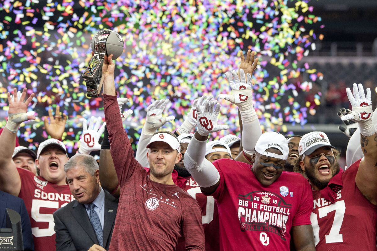 FILE - In this Dec. 7, 2019, file photo, Oklahoma head coach Lincoln Riley hosts the Big 12 Conference championship trophy after defeating Baylor 30-23 in overtime in an NCAA college football game in Arlington, Texas. Riley will earn an average of more than $7.5 million a year under a contract extension through the 2025 season. The university's board of regents approved the two-year extension Tuesday, July 28, 2020. (AP Photo/Jeffrey McWhorter, File)