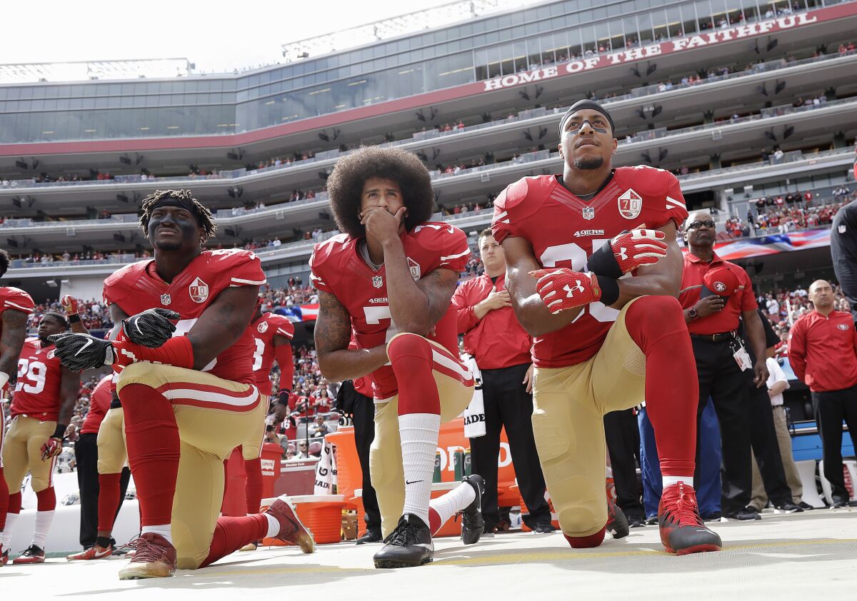 San Francisco 49ers' Eli Harold, left, Colin Kaepernick and Eric Reid kneel during the national anthem