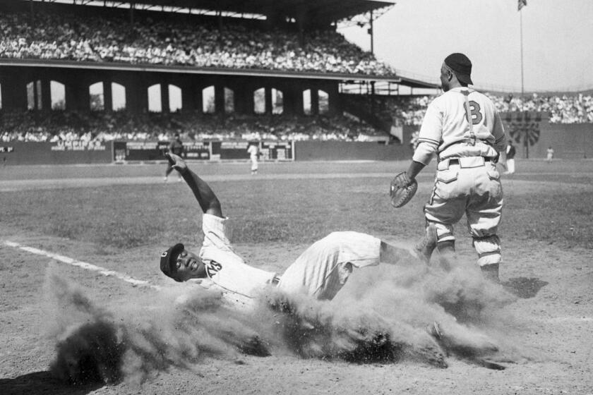 During the 12th annual East-West All-Star Game of the Negro Leagues, American baseball player Josh Gibson (1911 - 1947), of the East team, creates a cloud of dust as he slides into home plate during the fourth inning, Comiskey Park, Chicago, Illinois, August 13, 1944. West team’s catcher Ted Radcliffe (1902 - 2005) is visible at right. The West defeated the East, 7-4.