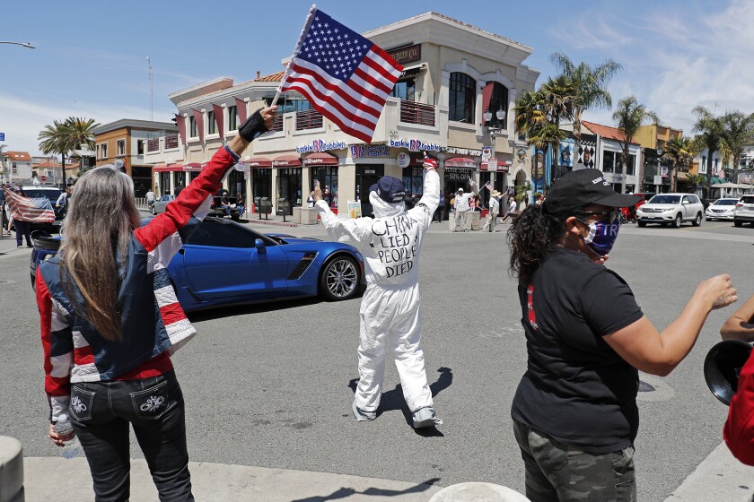 A message written on a man’s back reads, “CHINA LIED PEOPLE DIED,” as demonstrators crowd the intersection at Main Street and Walnut Avenue in downtown Huntington Beach on Friday.