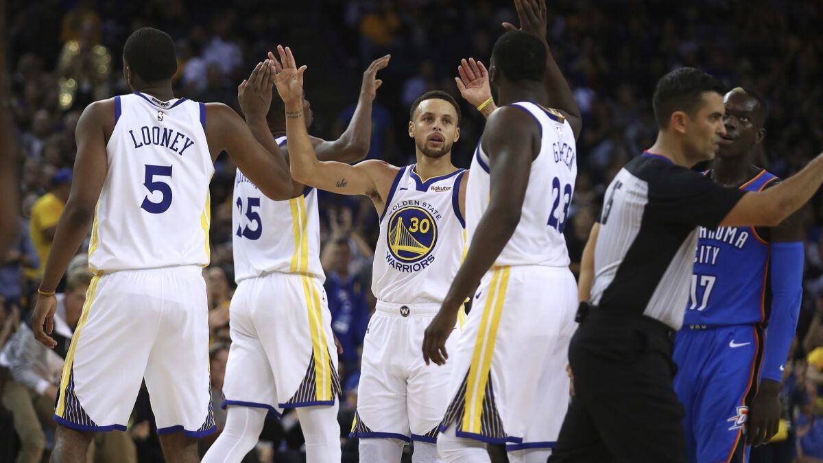 The Golden State Warriors' Stephen Curry celebrates with teammates as a foul is called against the Oklahoma City Thunder in the second half of their Oct. 16 game in Oakland.