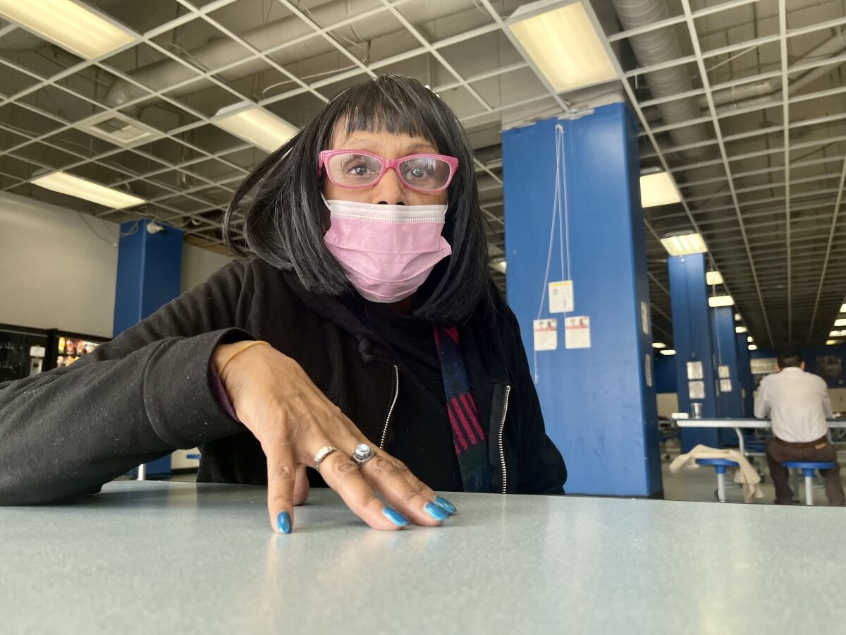 Margo Fitzsimmons, 66, sits at a table wearing a mask.