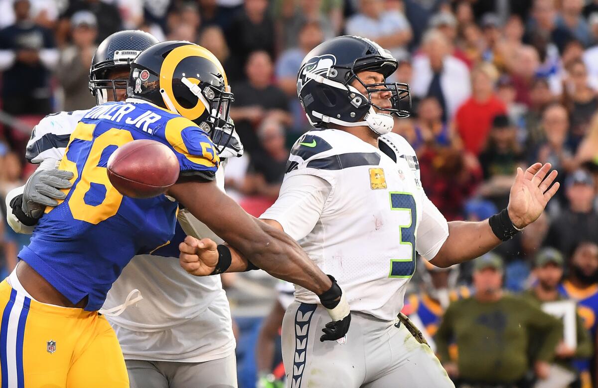 Rams linebacker Dante Fowler forces a fumble by Seattle Seahawks quarterback Russell Wilson in the fourth quarter of their game at the Coliseum last season, a key play in L.A.'s 36-31 victory.