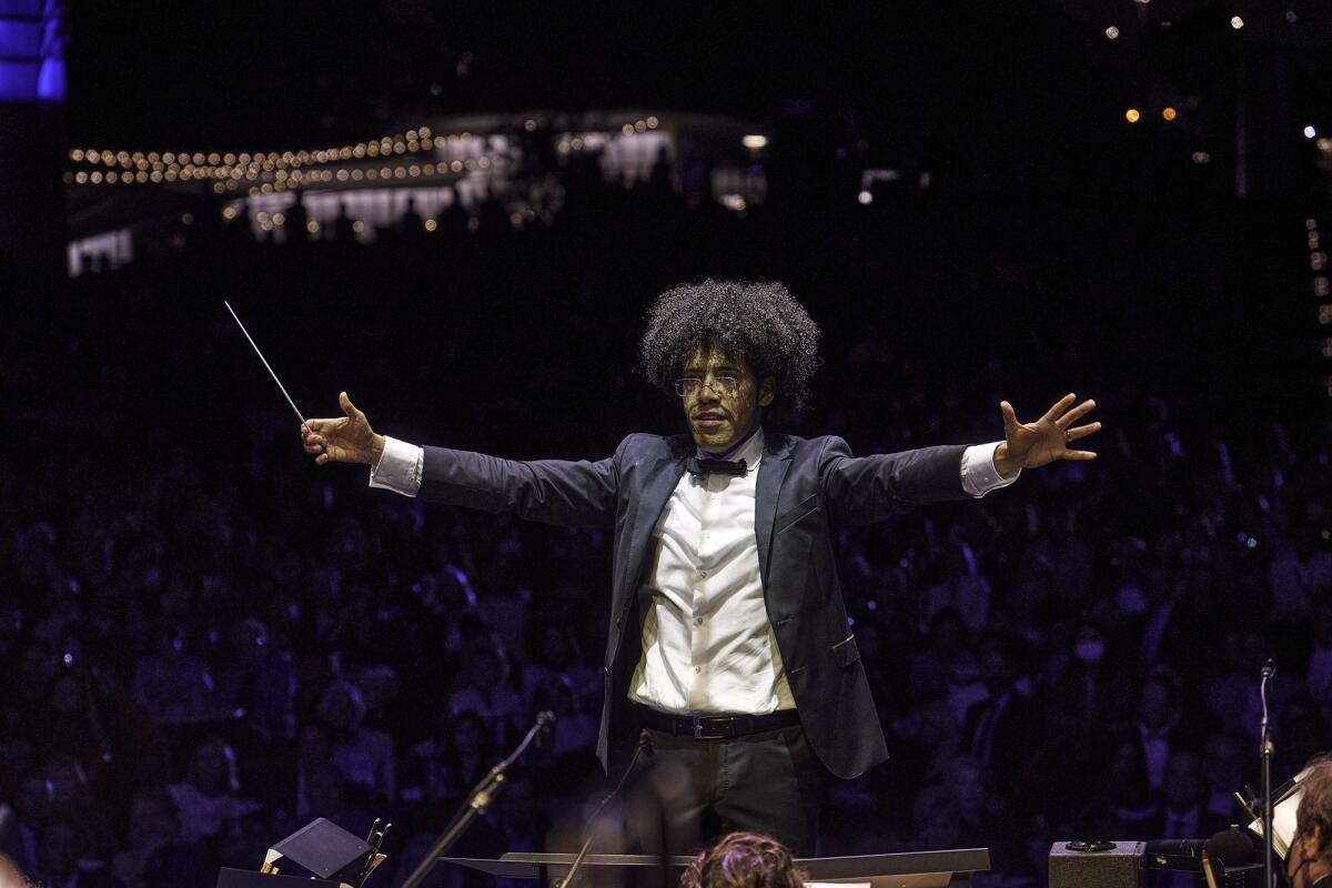 A conductor raises his arms.