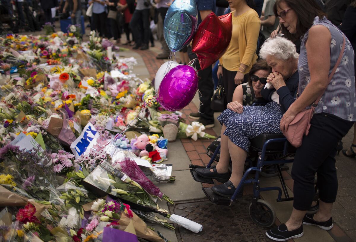 FILE - In this May 24, 2017 file photo women cry after placing flowers in a square in central Manchester, Britain, after the suicide attack at an Ariana Grande concert that left more than 20 people dead and many more injured, as it ended on Monday night at the Manchester Arena. (AP Photo/Emilio Morenatti, File)