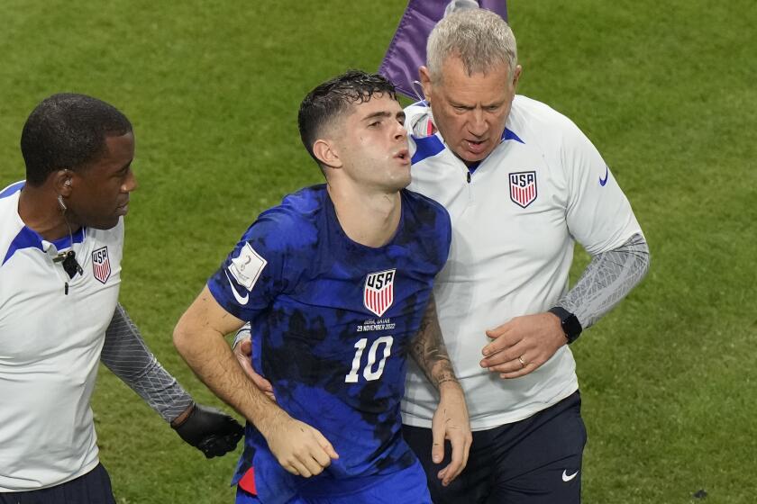 Christian Pulisic of the United States is helped by team doctors after he scoring his side's opening goal.