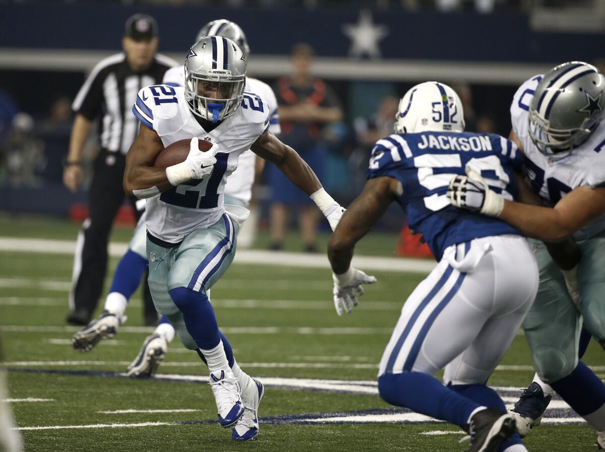Dallas Cowboys running back Joseph Randle runs the ball as Indianapolis Colts' D'Qwell Jackson closes in for a tackle during an NFL football game.