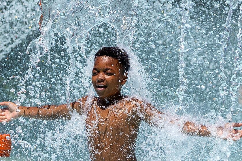 Los Angeles, CA - August 21: Majay Smith, 11, of Los Angeles, cools off amidst high temperatures at the LA84 Foundation/John C. Argue Swim Stadium spray pool in Los Angeles Wednesday, Aug. 21, 2024. (Allen J. Schaben / Los Angeles Times)