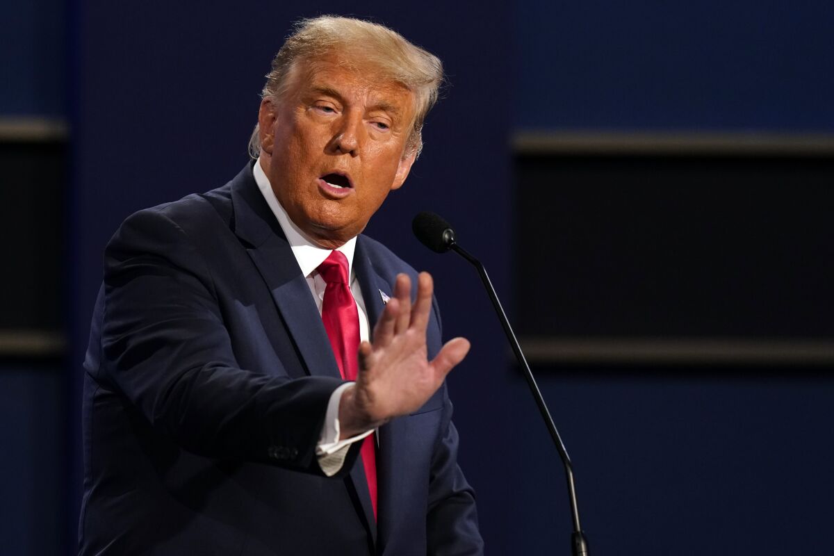 President Trump holds out his right hand as he speaks onstage during the debate