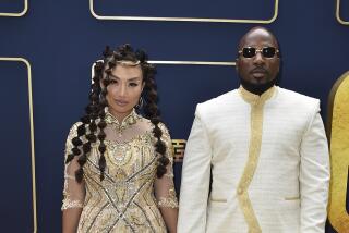 Jeannie Mai Jenkins in intricate gold gown holding hands with Jeezy in a white tunic and pants