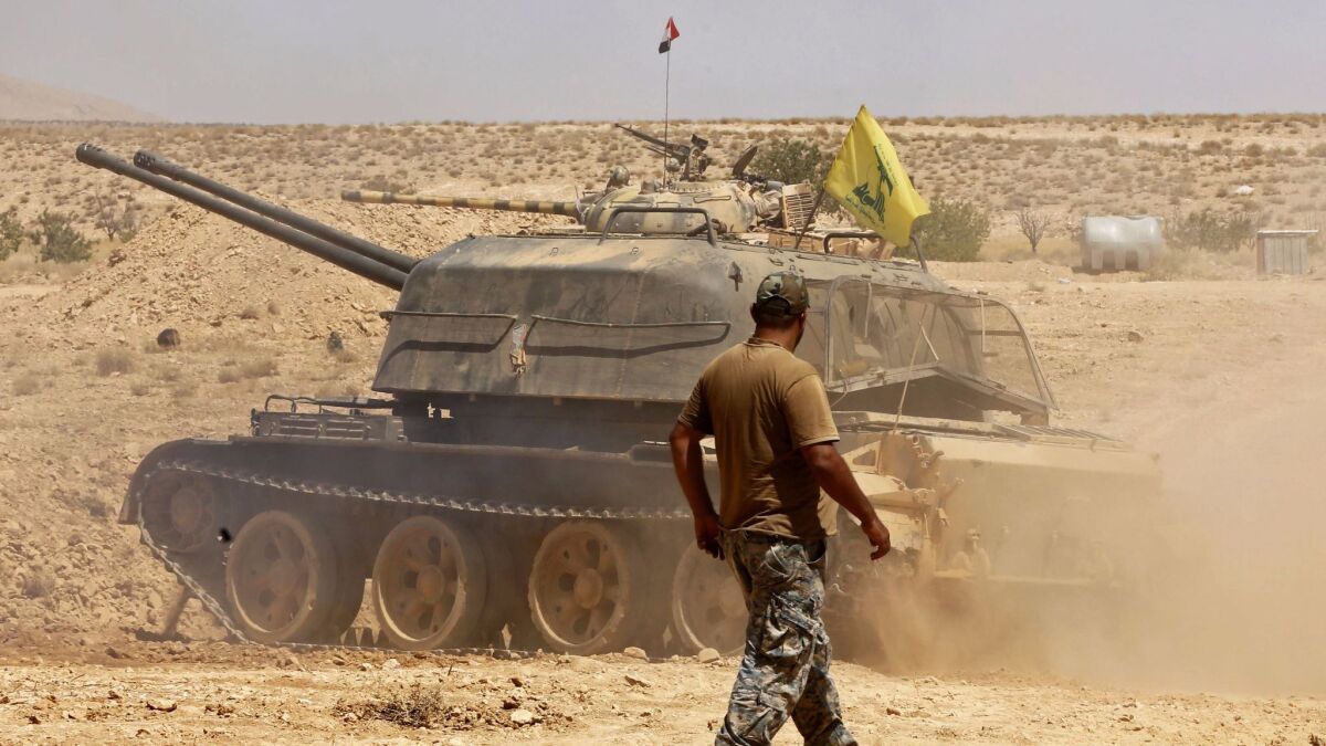 A fighter walks past a tank bearing a Hezbollah flag in the Qara area, in Syria's Qalamoun region, on Aug. 28, 2017.