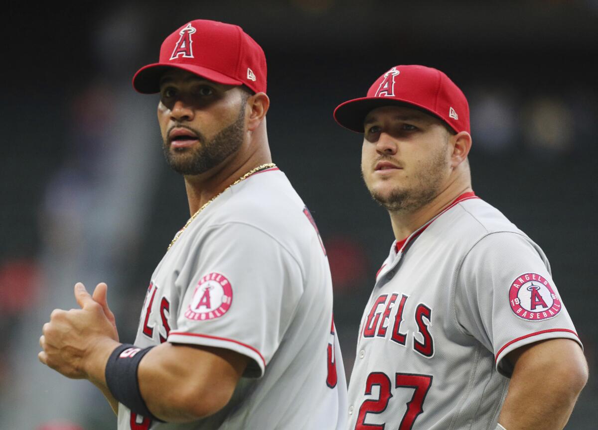 Angels first baseman Albert Pujols, left, and center fielder Mike Trout stand on the field.