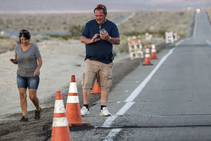 SEARLES VALLEY, CA - JULY 06, 2019 ? Michelle Binion, 56, left, and Gary Binion, 58, came from Rancho Cucamonga to photograph and to see how earthquake has ruptured roads and earth in the area. Geologists, tourists, students and others traveled from near and far to visit the surface ruptures crossing Highway 178 caused by Thursday?s 6.4 and Friday?s 7.1 earthquake. Tourists sent social media feeds to their friends and families. Geologists measured and studied the cracks in the road. Others hiked into the desert to follow the zig-zag path of the ruptures. Almost everyone snapped at least a couple of pictures. These fault ruptures functioned as small sources of wonder and enchantment for communities rocked by fear in the last few days. (Irfan Khan / Los Angeles Times)