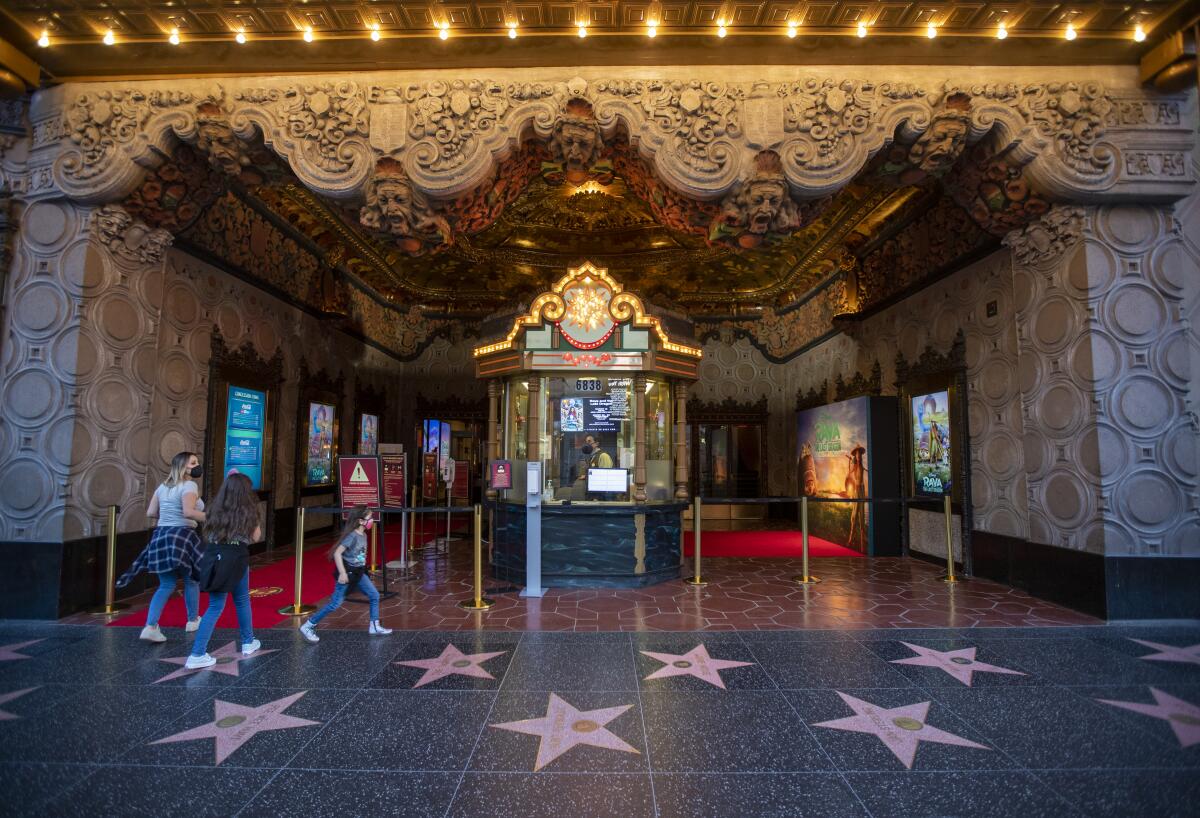 A movie theater host sits in a ticket booth at an ornate theater on the Hollywood Walk of Fame